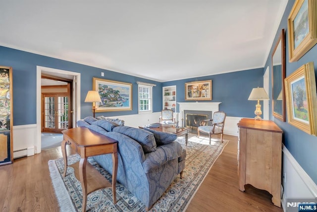 living area featuring a glass covered fireplace, wood finished floors, a wainscoted wall, and baseboard heating