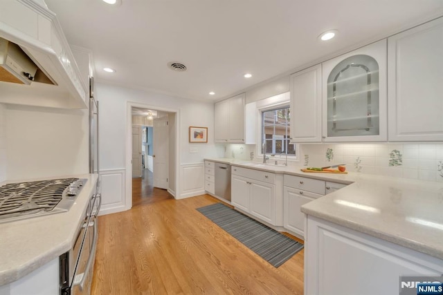 kitchen featuring visible vents, appliances with stainless steel finishes, light wood-style floors, white cabinets, and a sink