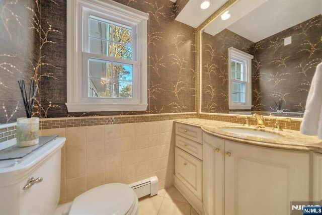 half bathroom featuring tile patterned floors, toilet, tile walls, a baseboard radiator, and vanity