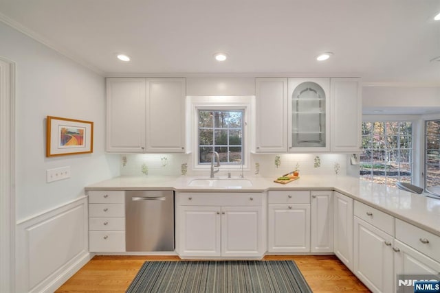 kitchen featuring a sink, light wood-style floors, dishwasher, and white cabinetry