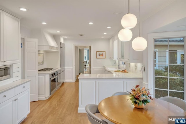 kitchen featuring white cabinets, stainless steel appliances, custom range hood, and a sink