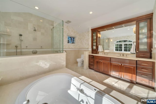 bathroom with vanity, a bath, a tile shower, wainscoting, and toilet