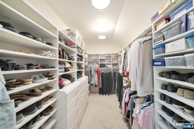 spacious closet with lofted ceiling and light carpet