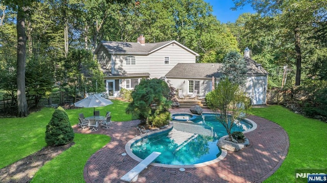 view of swimming pool featuring a yard, a patio, a fenced backyard, and a pool with connected hot tub