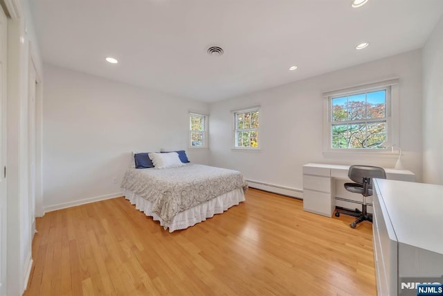 bedroom with light wood-type flooring, visible vents, baseboard heating, and recessed lighting