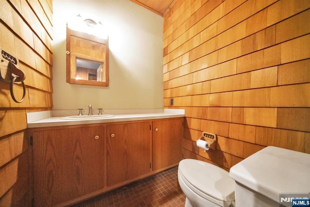 bathroom with tile patterned floors, wooden walls, vanity, and toilet