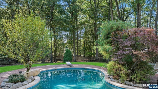 outdoor pool featuring a diving board, a yard, and fence