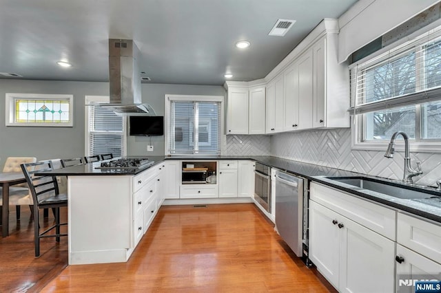 kitchen featuring stainless steel appliances, white cabinetry, sink, and a breakfast bar