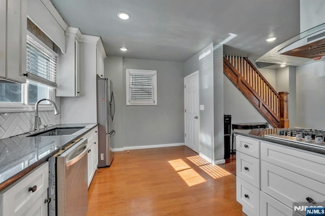 kitchen featuring sink, light hardwood / wood-style flooring, white cabinetry, stainless steel appliances, and decorative backsplash