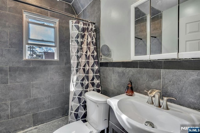 bathroom with a shower with curtain, toilet, sink, and tile walls