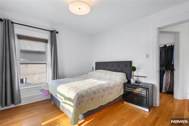 bedroom featuring a walk in closet, a closet, and hardwood / wood-style flooring