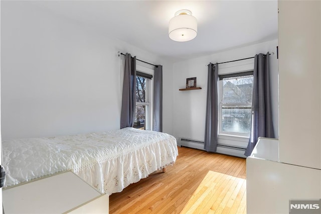 bedroom featuring wood-type flooring and a baseboard radiator