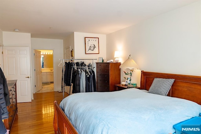 bedroom with light hardwood / wood-style floors, ensuite bathroom, and a closet