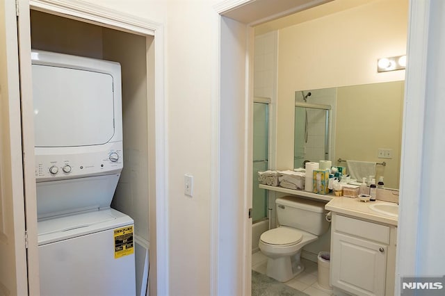 interior space with toilet, shower / bath combination with glass door, tile patterned floors, stacked washer and clothes dryer, and vanity