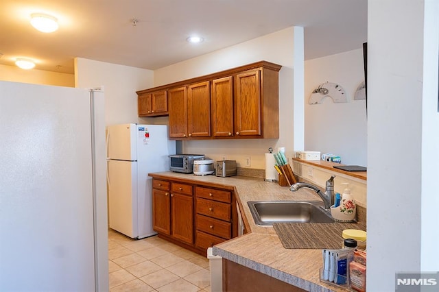 kitchen with sink, white refrigerator, and light tile patterned flooring