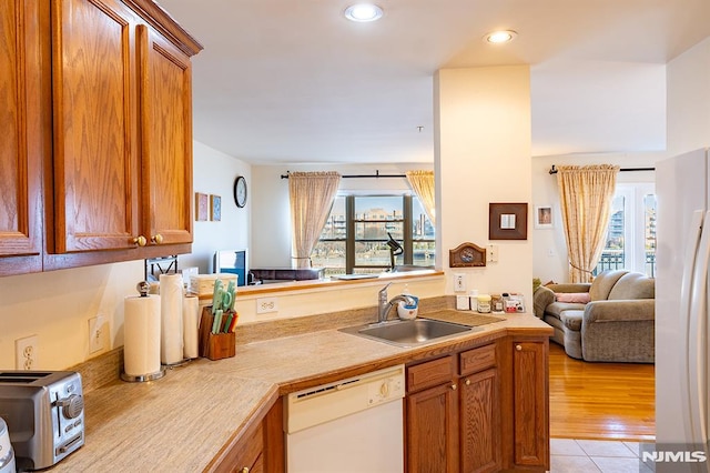 kitchen featuring sink, white appliances, light tile patterned floors, and kitchen peninsula