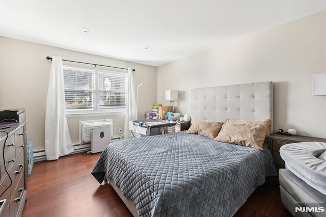 bedroom with a baseboard heating unit and dark hardwood / wood-style flooring