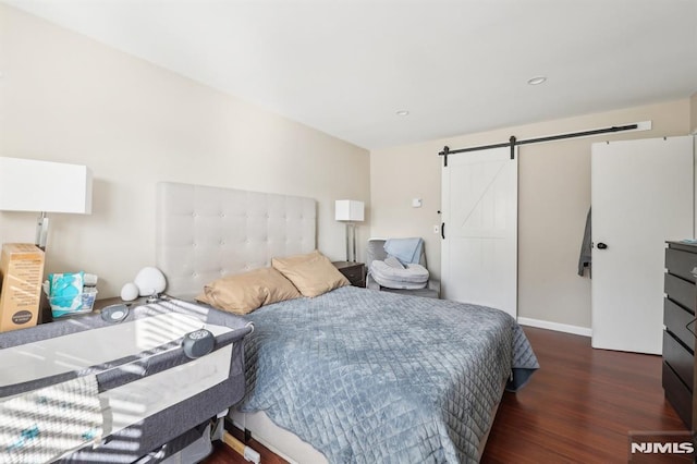 bedroom featuring dark hardwood / wood-style floors and a barn door