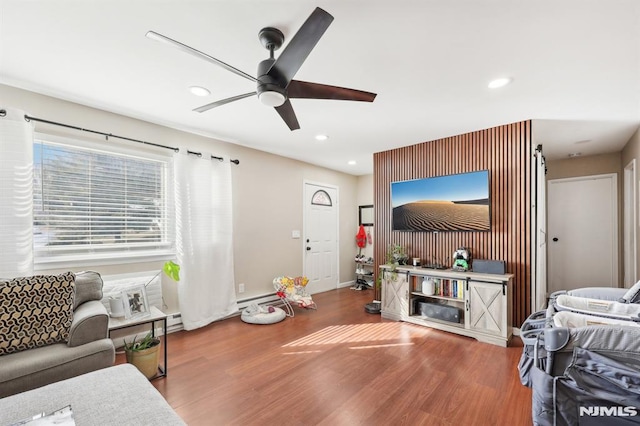 living room with ceiling fan, baseboard heating, and wood-type flooring