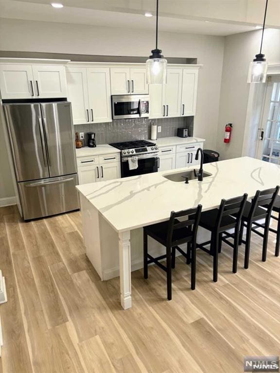 kitchen with decorative light fixtures, white cabinets, appliances with stainless steel finishes, and sink