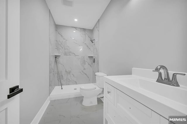 bathroom with a tile shower, vanity, and toilet