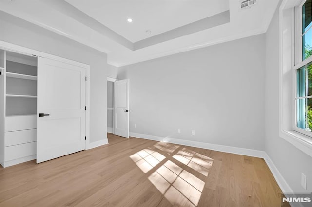 unfurnished bedroom with light hardwood / wood-style flooring and a raised ceiling