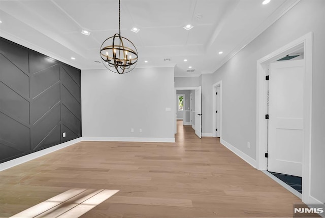 unfurnished dining area featuring light wood-type flooring, an inviting chandelier, and a raised ceiling