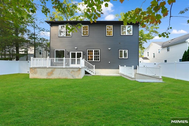 back of property featuring a lawn and a deck