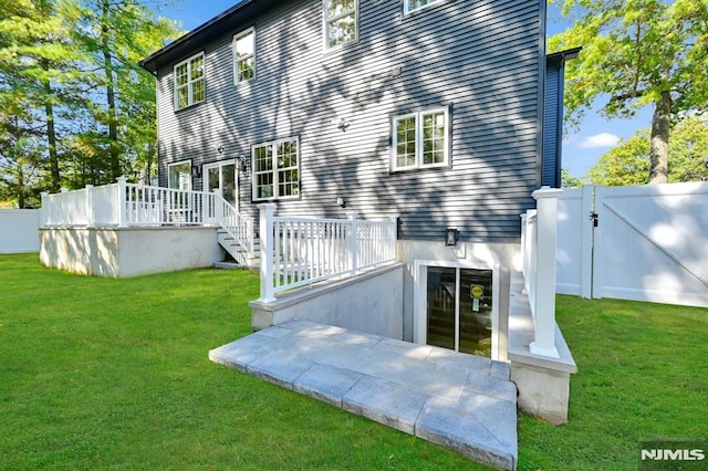 rear view of property with a deck and a lawn