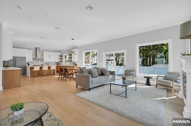 living room with light hardwood / wood-style floors, a notable chandelier, and ornamental molding