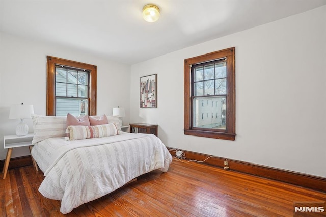 bedroom with multiple windows and dark hardwood / wood-style floors