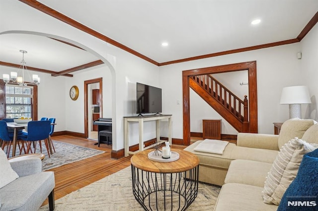 living room featuring a notable chandelier, crown molding, and light hardwood / wood-style flooring