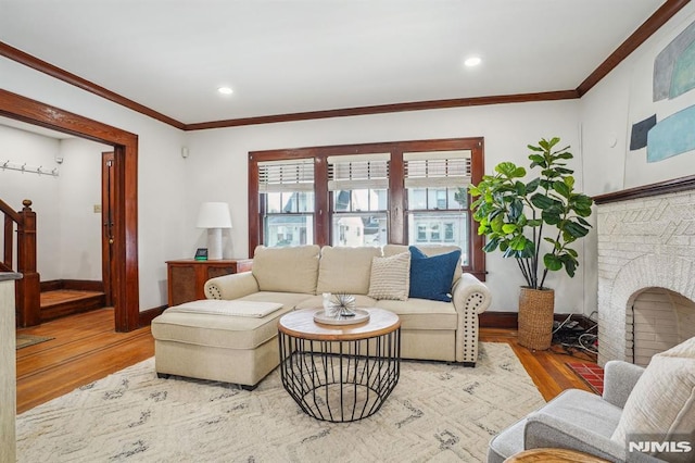 living room with a brick fireplace, ornamental molding, and hardwood / wood-style flooring