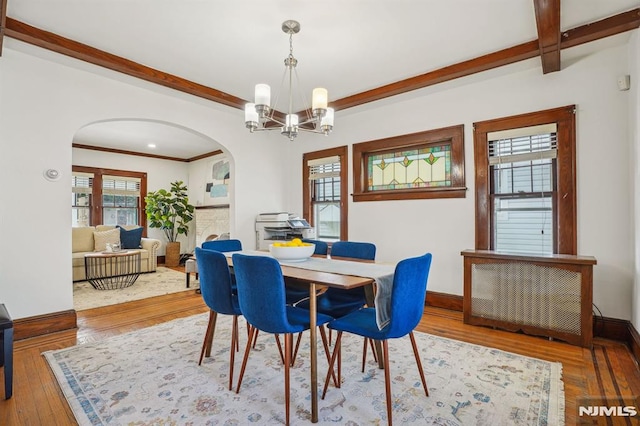 dining area with ornamental molding, a chandelier, and hardwood / wood-style floors