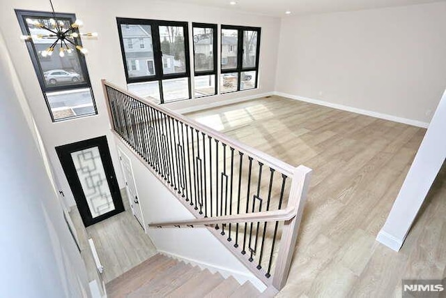 staircase featuring hardwood / wood-style flooring, a wealth of natural light, and a chandelier