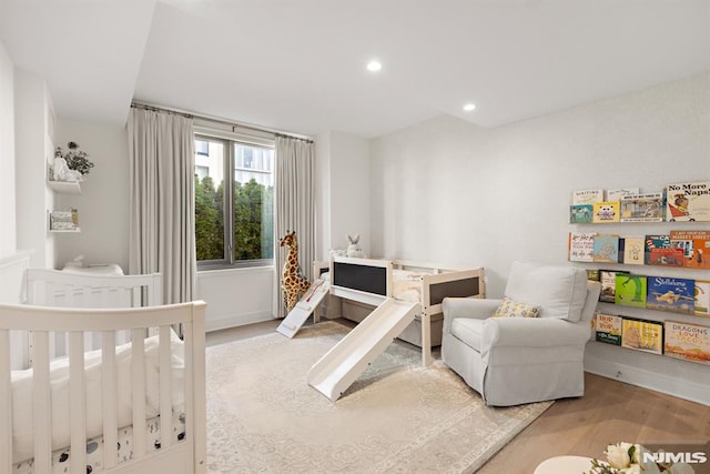 bedroom with a nursery area and light hardwood / wood-style flooring