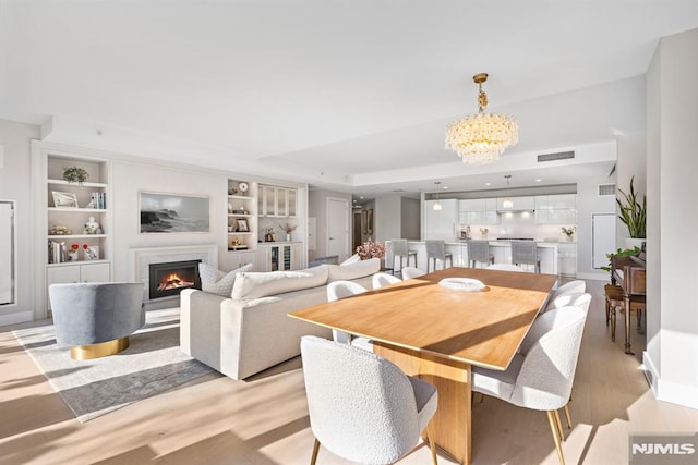 dining room featuring an inviting chandelier, light wood-type flooring, and built in features