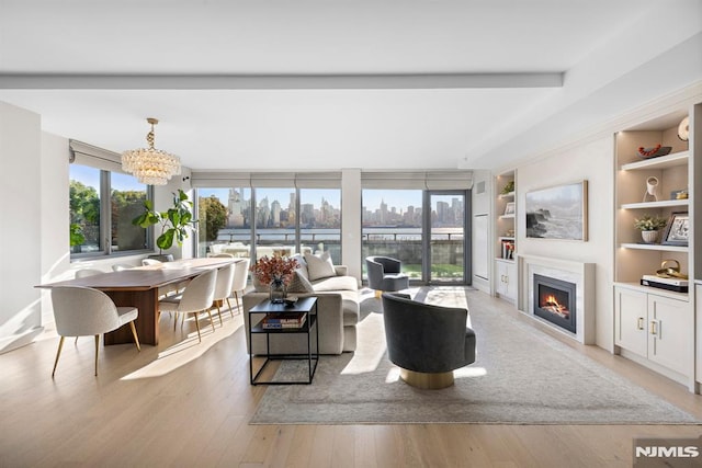 living room featuring built in features, a notable chandelier, and light hardwood / wood-style flooring