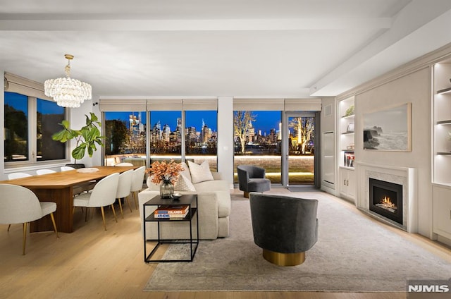 living room with floor to ceiling windows, light hardwood / wood-style flooring, a chandelier, beam ceiling, and a high end fireplace