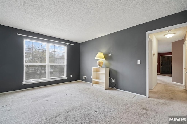 empty room with light colored carpet and a textured ceiling