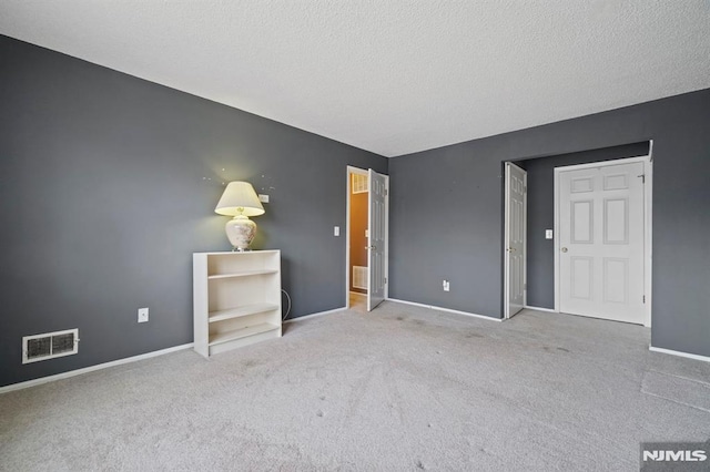 unfurnished room featuring carpet and a textured ceiling