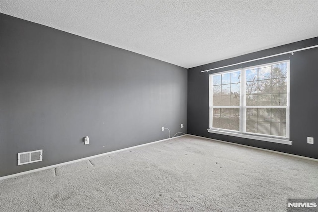 unfurnished room with a textured ceiling and carpet flooring