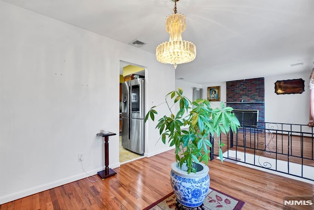 dining space with a fireplace, an inviting chandelier, and wood-type flooring