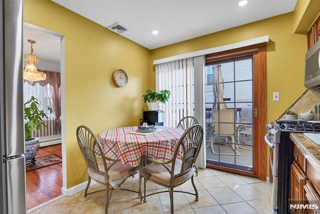 dining area with a wealth of natural light, a notable chandelier, light tile patterned flooring, and a baseboard heating unit