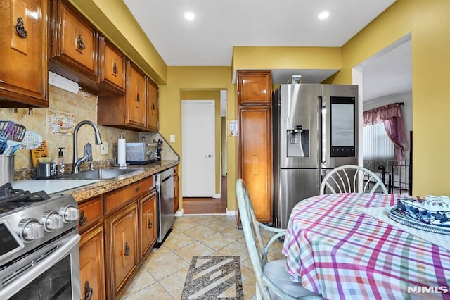 kitchen featuring stainless steel appliances, light tile patterned floors, tasteful backsplash, and sink