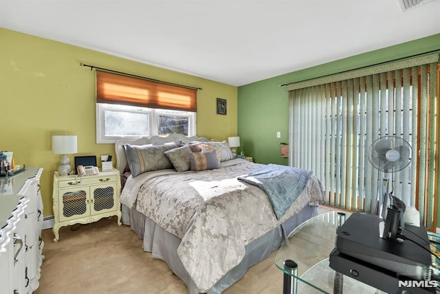 bedroom with a baseboard heating unit and light colored carpet