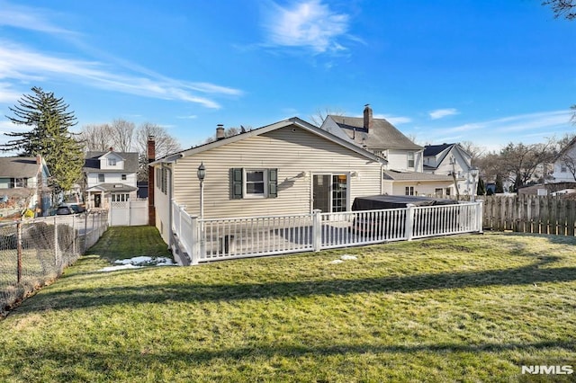 back of property with a yard and a hot tub