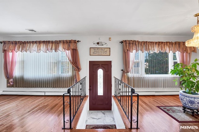 entryway with a baseboard heating unit, wood-type flooring, and an inviting chandelier