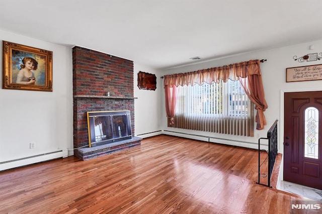 unfurnished living room with wood-type flooring, a fireplace, and baseboard heating