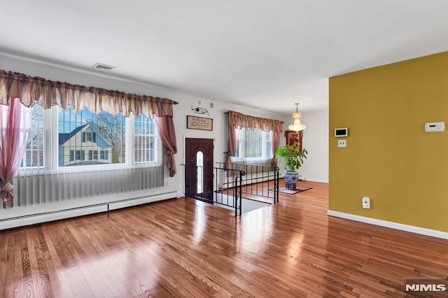 empty room with wood-type flooring and a baseboard radiator